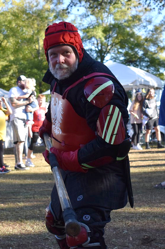Older gentleman in fencing gear holding a quarterstaff